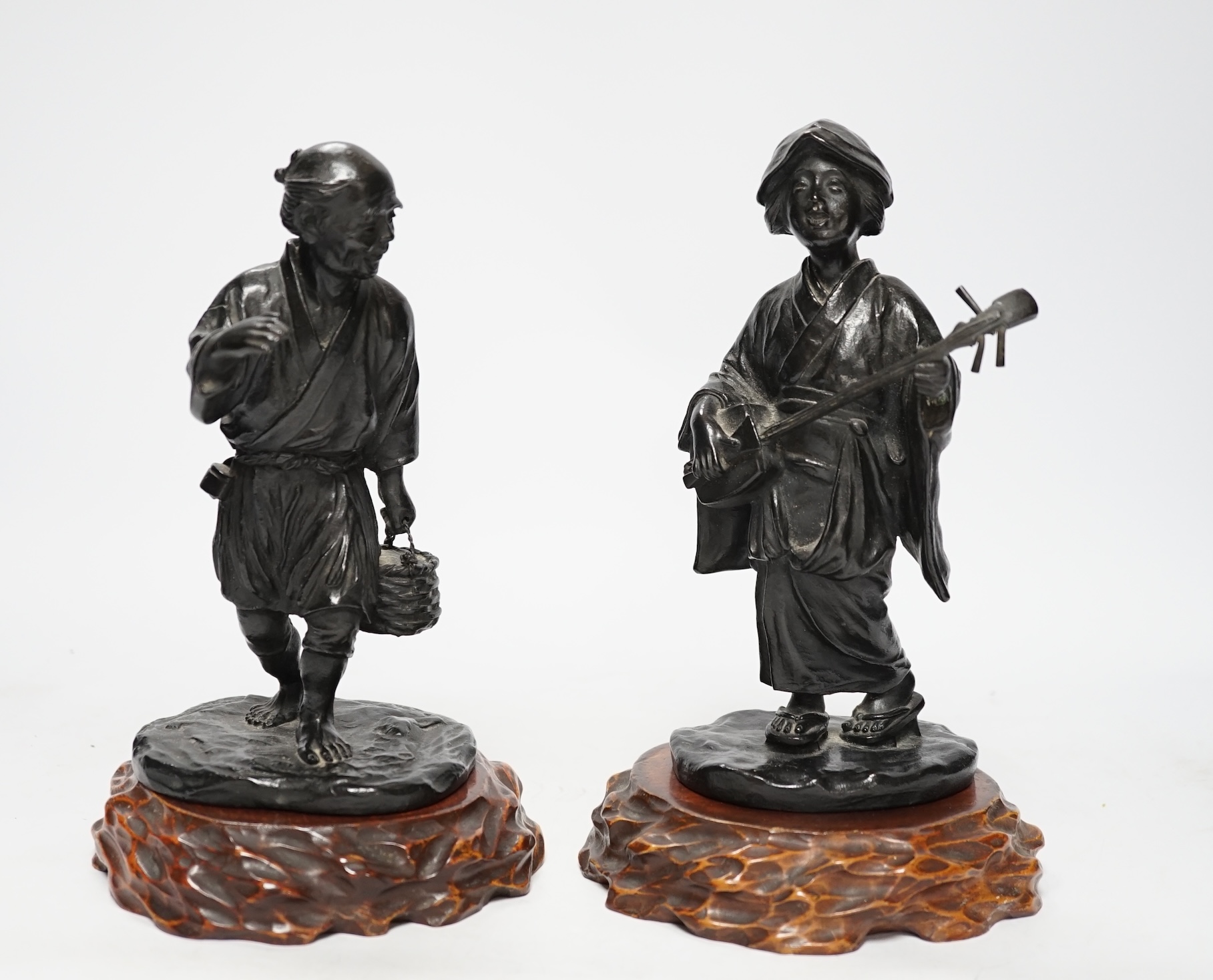 Two Japanese Meiji period bronzes, a water carrier and a woman playing a Shamisen, both signed, each with wooden plinths, largest 22cm high